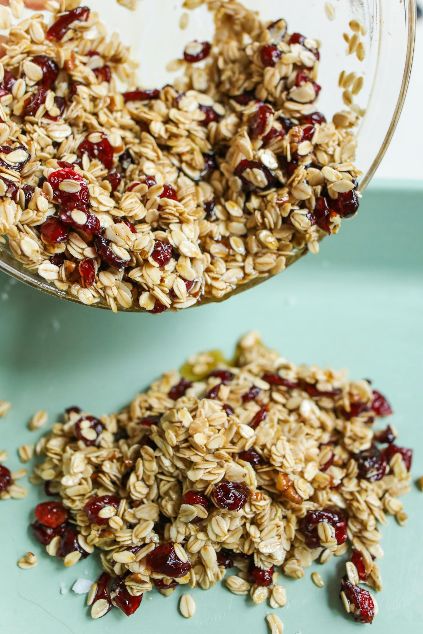Close-up of homemade granola with oats and cranberries pouring from a bowl.