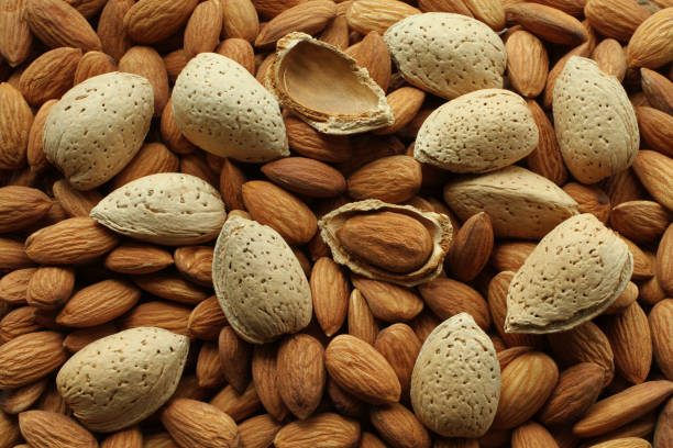 Top view of a pile of peeled raw almonds and raw almonds with shells. closeup